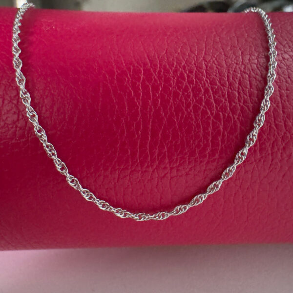 Chic simple silver anklet draped over a red purse.