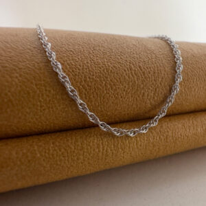 Close up of a simple and chic silver chain hung over a mustard purse.