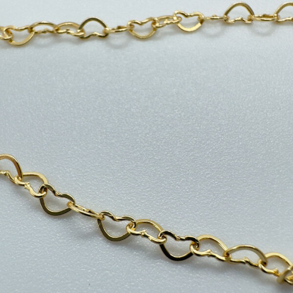 Close up of Identical gold hearts interlinked to make a dainty anklet.