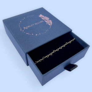 Identical gold hearts interlinked to make a dainty anklet presented in a dark blue Anklet Allure gift box.
