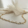 Stunning gold anklet made of interlinking identical hearts draped over a white feather.