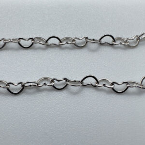 Close up of identical silver hearts interlinked to make a dainty anklet.