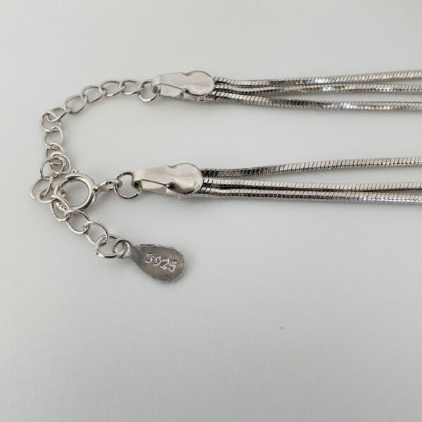 Close up of triple chain silver anklet with 925 sterling silver stamp.
