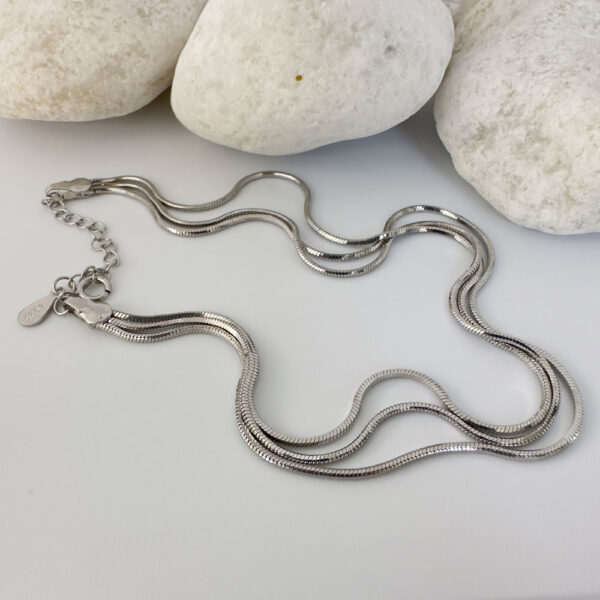 Triple chain silver anklet with white rocks behind.