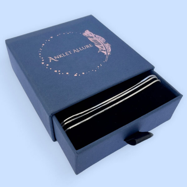 Triple chain silver anklet in a blue jewellery box.