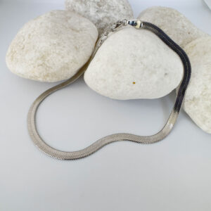 Thick silver snake chain anklet on white rocks.