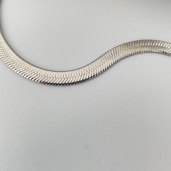Close up of a thick silver snake chain anklet.