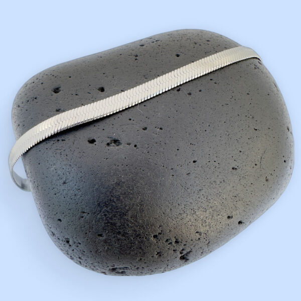 Thick silver snake chain anklet on a black rock.
