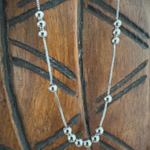 Silver anklet with six balls in one section then a single ball either side and then three balls grouped together after that.