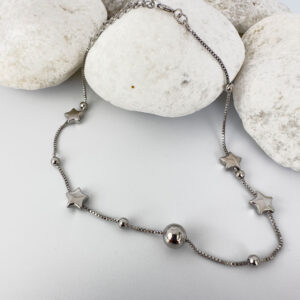 Silver anklet with solid star and ball charms on white rocks.