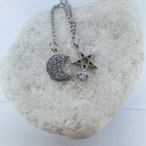 Ankle bracelet with a five pointed star and a crescent moon, both diamond encrusted, on a white rock.