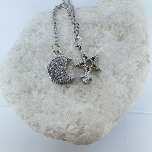 Ankle bracelet with a five pointed star and a crescent moon, both diamond encrusted, on a white rock.