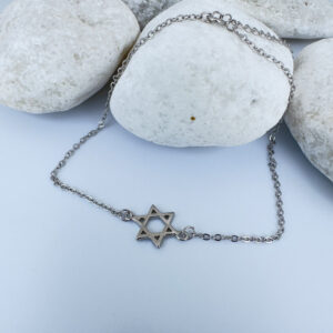 Silver anklet with a star of David charm on white rocks.
