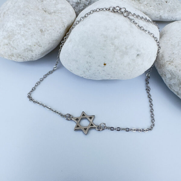 Silver anklet with a star of David charm on white rocks.