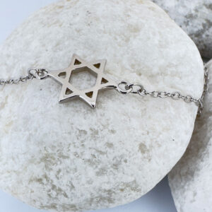 Silver anklet with a star of David charm on a white rock.