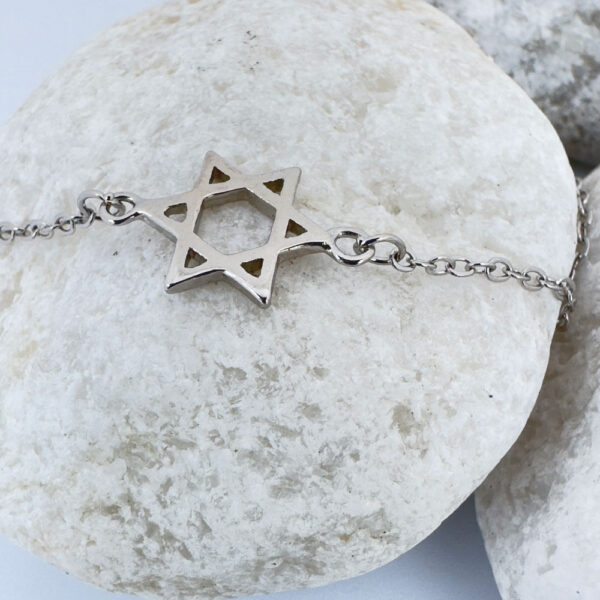 Silver anklet with a star of David charm on a white rock.