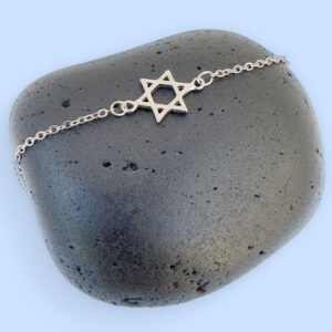 Silver anklet with a star of David charm on a black rock.