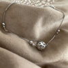 Sterling Silver anklet with a globe like ball as the main feature and smaller balls around the chain in pairs, one bigger than the other.