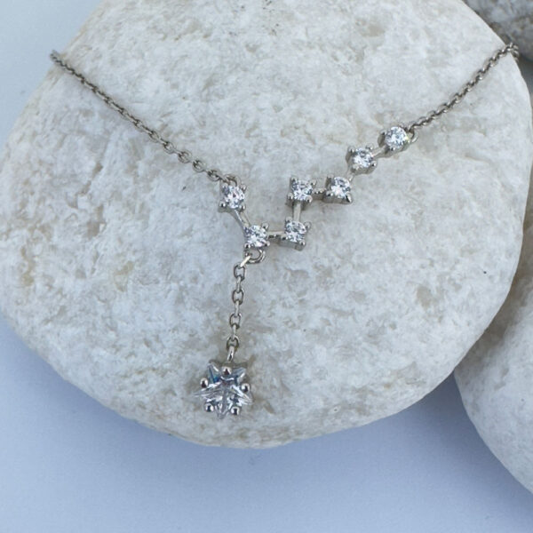 Celestial anklet with seven white gemstones and a large gemstone hanging down on a white rock.