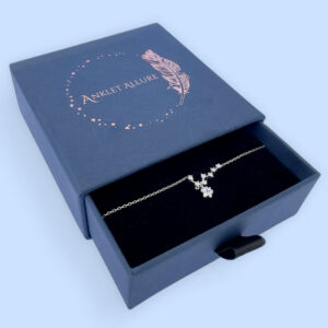 Celestial anklet with seven white gemstones and a large gemstone hanging down, in a blue Anklet Allure jewellery box.