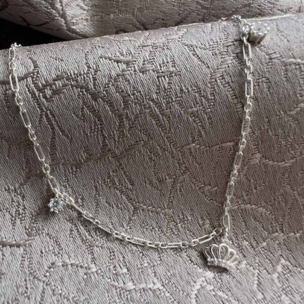 Regal sterling silver paperclip style ankle chain with two cubic zirconia gems on each side of the chain and a crown charm with cubic zirconia detail in the middle.