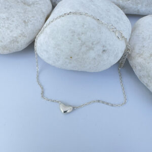 Stunning silver ankle bracelet with a cute solid silver heart charm on a white rock.