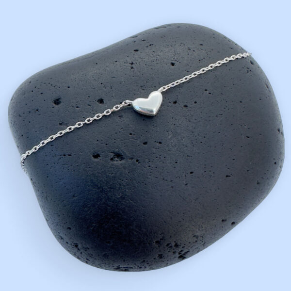 Stunning silver anklet with a cute solid silver heart charm on a black rock.