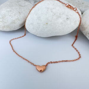 Stunning rose gold anklet with a cute solid rose gold heart charm on white rocks.