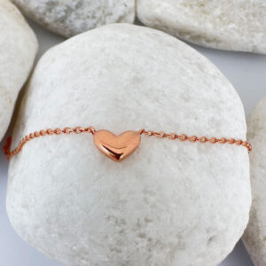 Stunning rose gold anklet with a cute solid rose gold heart charm on a white rock.