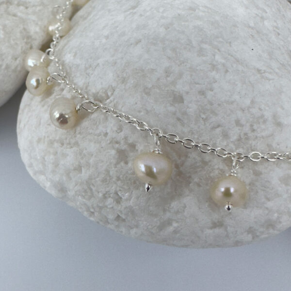 Close up of feminine anklet with freshwater pearls hanging all the way around.