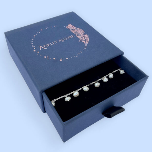 Amazing anklet with freshwater pearls hanging all the way around, presented in a blue jewellery box with Anklet Allure written on the top in rose gold.