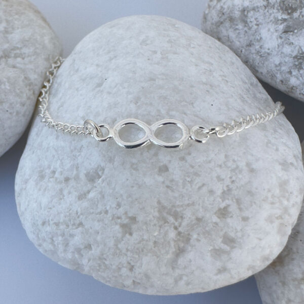 Chunky silver infinity chain anklet on a white rock.