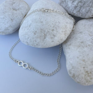 Chunky silver infinity chain anklet on white rocks.