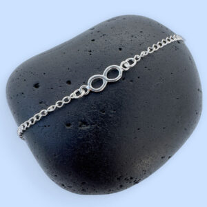 Chunky silver infinity chain anklet on a black rock.