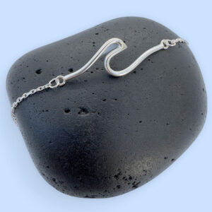 Sterling silver anklet with a surf wave design on a black rock.