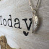 Sterling silver anklet with unique angel wing charm on wooden white washed background.