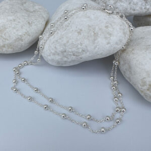 Woman's anklet in silver with small balls all the way around on white rocks.
