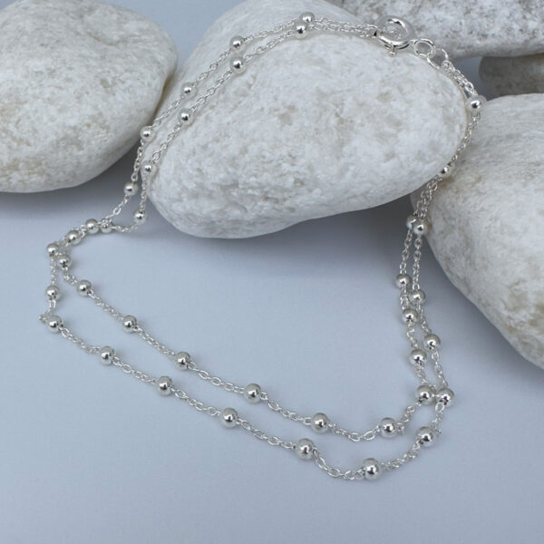Woman's anklet in silver with small balls all the way around on white rocks.