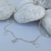Beautiful silver anklet with hoop and ball charms equally spaced around on white rocks.
