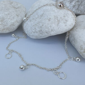 Beautiful silver anklet with hoop and ball charms equally spaced around on white rocks.