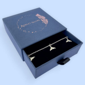 Anklet in silver with whale tail charms equally spaced around presented in a blue Anklet Allure jewellery box.